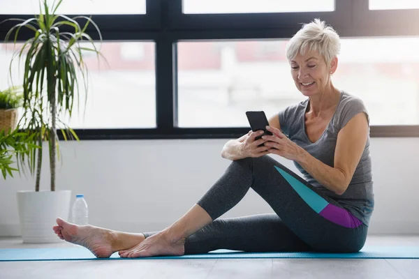 Donna Anziana Seduta Tappetino Yoga Con Telefono — Foto Stock