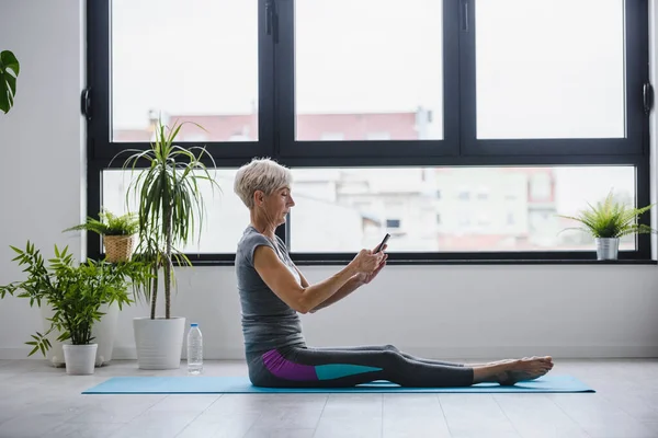 Donna Anziana Seduta Tappetino Yoga Con Telefono — Foto Stock