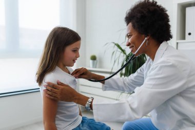 Afrikalı Amerikalı doktor küçük kızı muayene ediyor. 