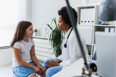 Afrikalı Amerikalı doktor küçük kızı muayene ediyor. 