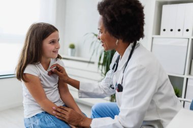 Afrikalı Amerikalı doktor küçük kızı muayene ediyor. 
