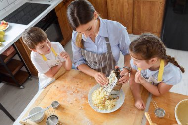 Anne, oğlu ve kızıyla yemek pişiriyor.