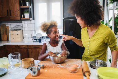 Afro-Amerikan ailesi anne ve kızı birlikte yemek pişiriyor.