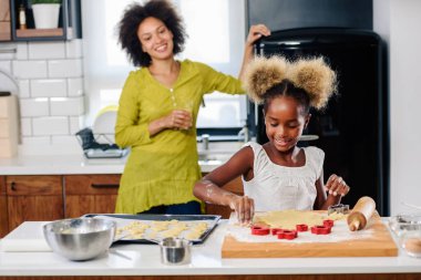 Afro-Amerikan ailesi anne ve kızı birlikte yemek pişiriyor.