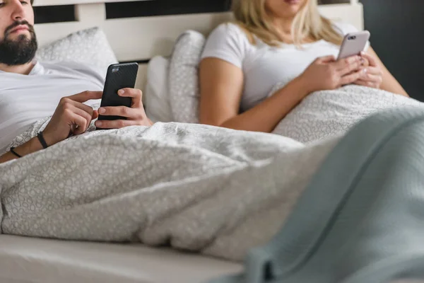 Upset Young Couple Lying Bed Using Smartphones — Stock Photo, Image