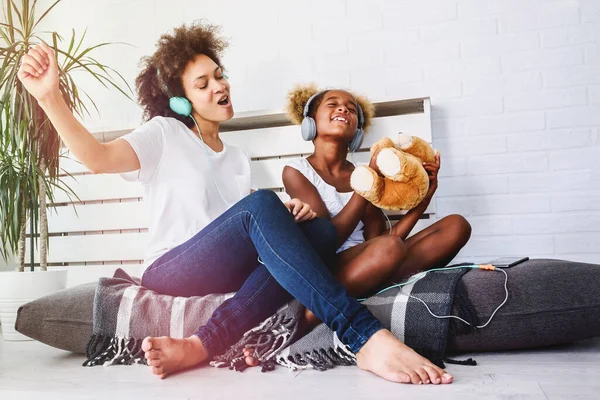 stock image Beautiful smiling African American mother and daughter having fun at home listening to music