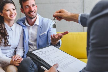 Emlakçı müşterilere anlaşma ve anahtar veriyor.