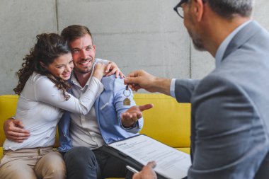 Emlakçı müşterilere anlaşma ve anahtar veriyor.