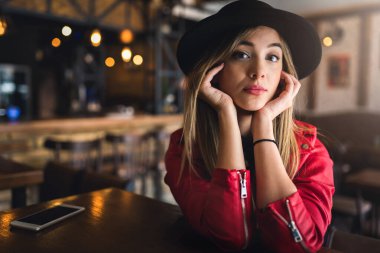 Kafede deri ceketli ve şapkalı güzel bir kadın..