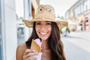 Şehir parkında lezzetli dondurmalar yiyen genç ve güzel bir kadın. 