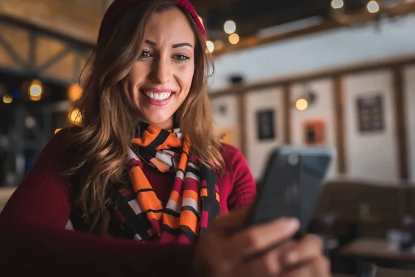 カフェで携帯電話を持っている幸せな若い女性 — ストック写真