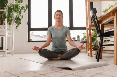 Evde esneme egzersizleri yapan çekici bir kız. Güzel bir kadın yoga ve meditasyon yapıyor.. 
