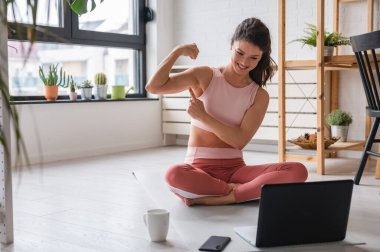 Laptop kullanan güzel genç bir kadın, online yoga dersleri alıyor. 