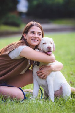 Genç bir kadın halka açık parkta şirin Labrador Retriever 'la oynuyor. Köpek en iyi arkadaş.