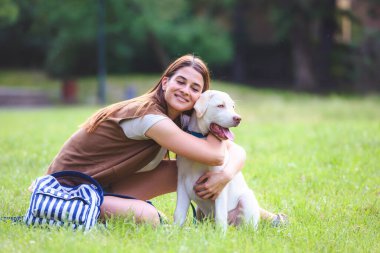Genç bir kadın halka açık parkta şirin Labrador Retriever 'la oynuyor. Köpek en iyi arkadaş.