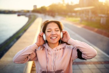 Genç bayan koşucu dinleniyor Nehir kenarında müzik dinliyor