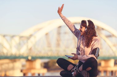 Genç bayan koşucu dinleniyor Nehir kenarında müzik dinliyor