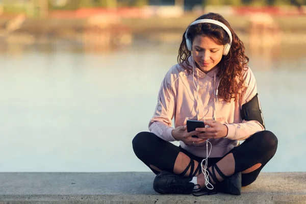 Молода Жінка Бігун Відпочиває Слухаючи Музику Біля Річки — стокове фото