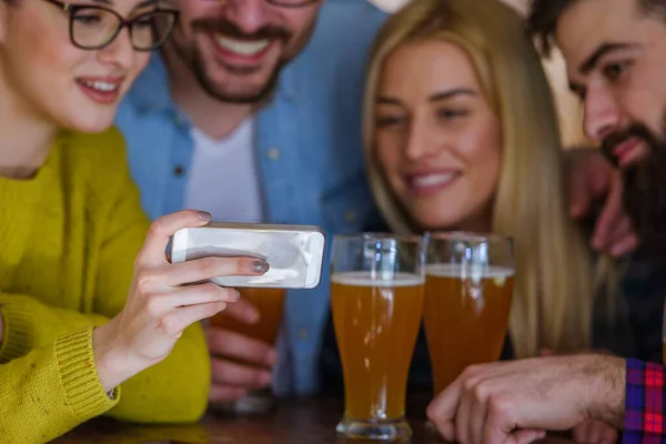 バーで友人スマートフォンを見てビールを飲む — ストック写真