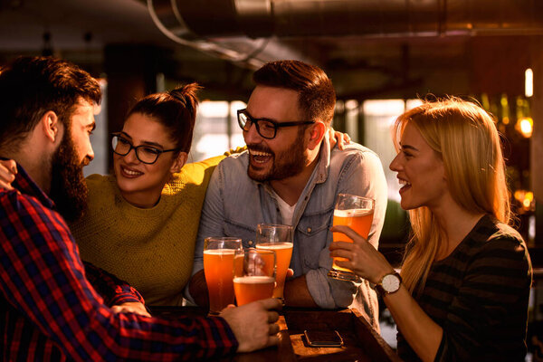 Group of young friends in bar drinking beer 