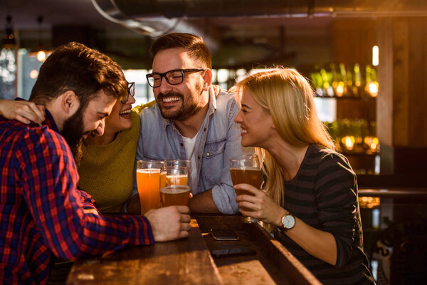 Group of young friends in bar drinking beer 