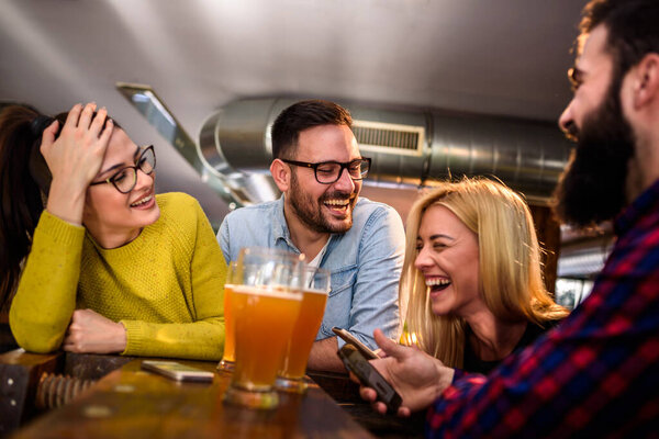 Friends at the bar drinking beer with smartphones