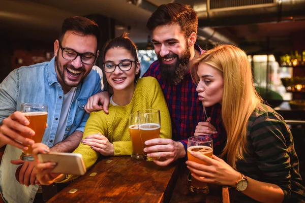 酒吧里的朋友们一边喝啤酒一边看智能手机 — 图库照片
