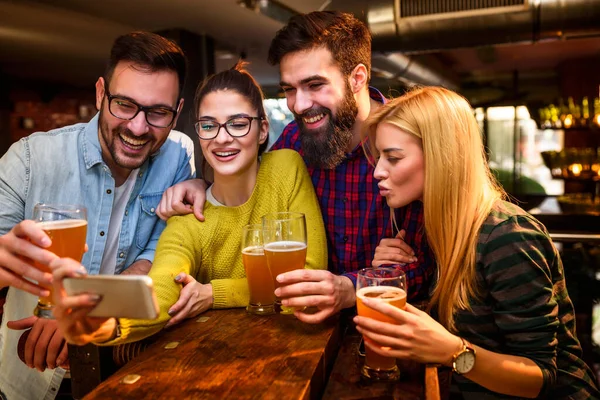 バーで友人スマートフォンを見てビールを飲む — ストック写真