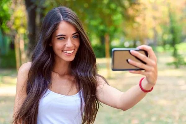 公園で携帯電話で自撮りしてる若い美少女 — ストック写真