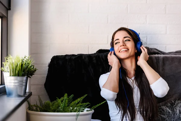 美丽的年轻黑发女子在耳机里听音乐 — 图库照片