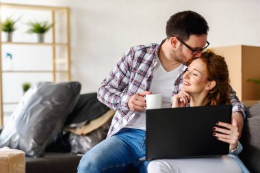 Mutlu çift yeni evinde dizüstü bilgisayar kullanıyor.