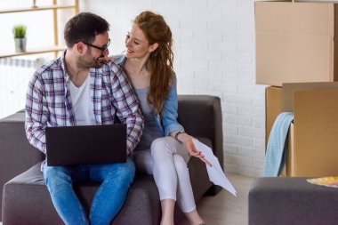 Mutlu çift yeni evinde dizüstü bilgisayar kullanıyor.