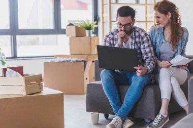Mutlu çift yeni evinde dizüstü bilgisayar kullanıyor.
