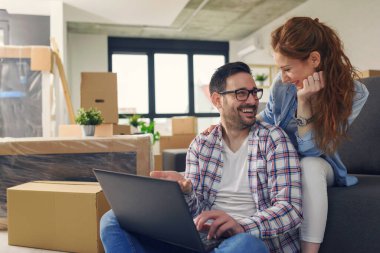 Mutlu çift yeni evinde dizüstü bilgisayar kullanıyor.