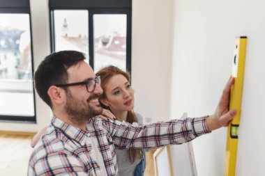 Boş bir dairede duvarları ölçen bir çift. Taşındıktan ve yenilendikten sonra etkinlikler.