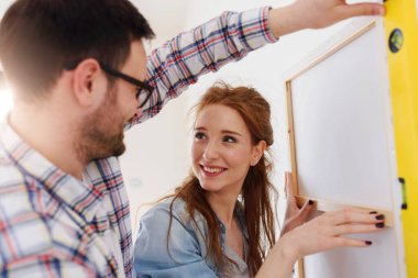 Boş bir dairede duvarları ölçen bir çift. Taşındıktan ve yenilendikten sonra etkinlikler.