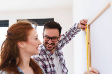 Boş bir dairede duvarları ölçen bir çift. Taşındıktan ve yenilendikten sonra etkinlikler.