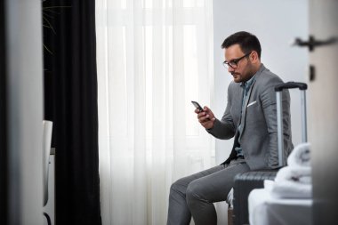 İş adamı otel odasında akıllı telefon kullanıyor. İş seyahati..