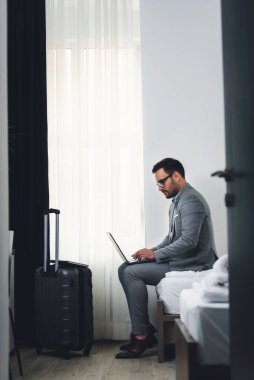İşadamı dizüstü bilgisayar kullanıyor, otel odasında çalışıyor. İş seyahati..
