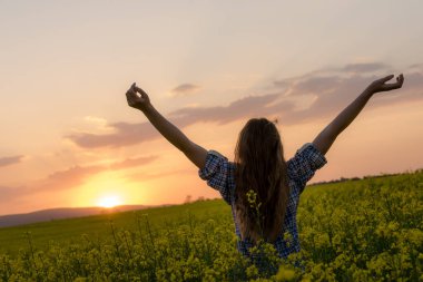 Gün batımında kanola sahasında poz veren güzel bir kadın