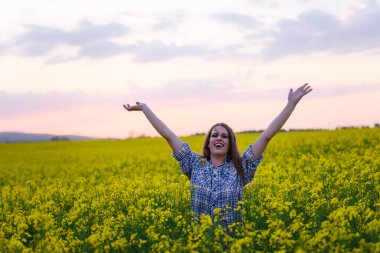 Gün batımında kanola sahasında poz veren güzel bir kadın