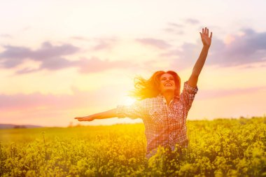 Gün batımında kanola sahasında poz veren güzel bir kadın