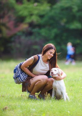 Güzel kız parkta labrador köpeğiyle eğleniyor.