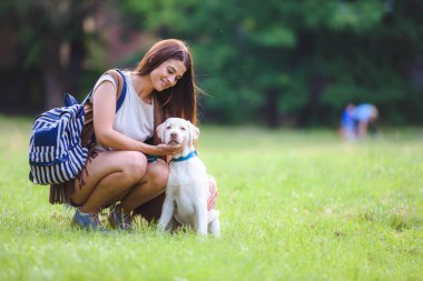 Güzel kız parkta labrador köpeğiyle eğleniyor.