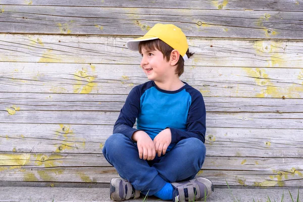 Szczęśliwy Chłopiec Żółtym Kapeluszu Siedzi Drewnianym Tle — Zdjęcie stockowe