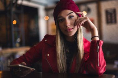 Kafede cep telefonu olan genç bir kadın. 