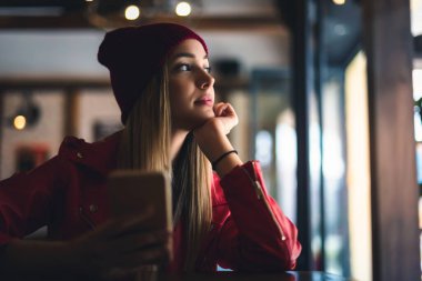 Kafede cep telefonu olan genç bir kadın. 