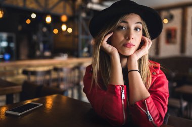 Kafede poz veren şapkalı güzel bir kadın.