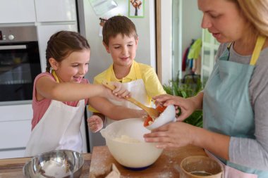 Anne, kız ve oğul birlikte hamur işi pişiriyor, hamurla çalışıyorlar.