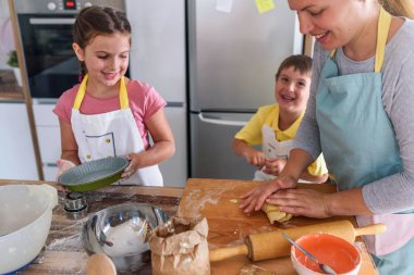 Anne, kız ve oğul birlikte hamur işi pişiriyor, hamurla çalışıyorlar.